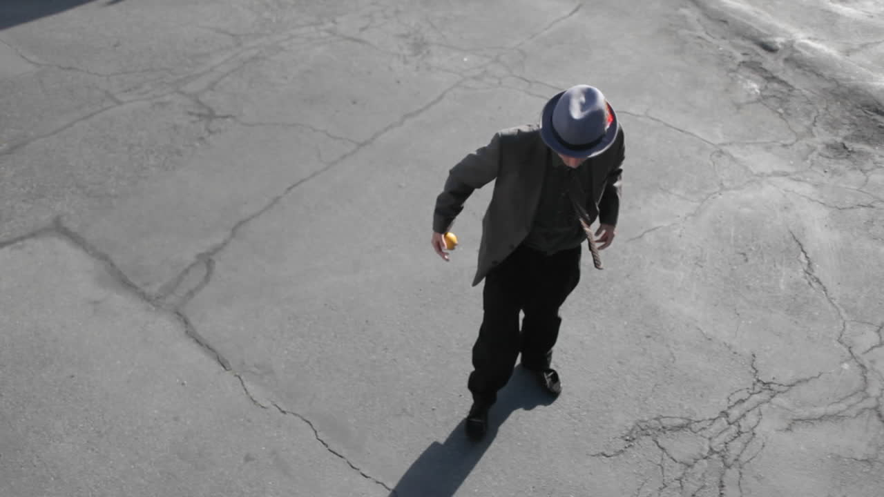 un hombre hace malabarismos con una pelota naranja con el pie