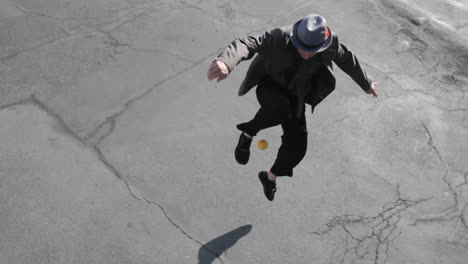 a man juggles an orange ball with his foot