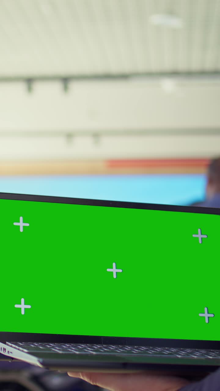 Hands Holding Laptop with Green Screen Display in Public Space