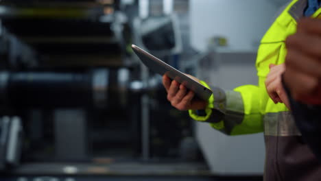 Closeup-hands-holding-tablet-computer-at-modern-huge-special-facility-storage.