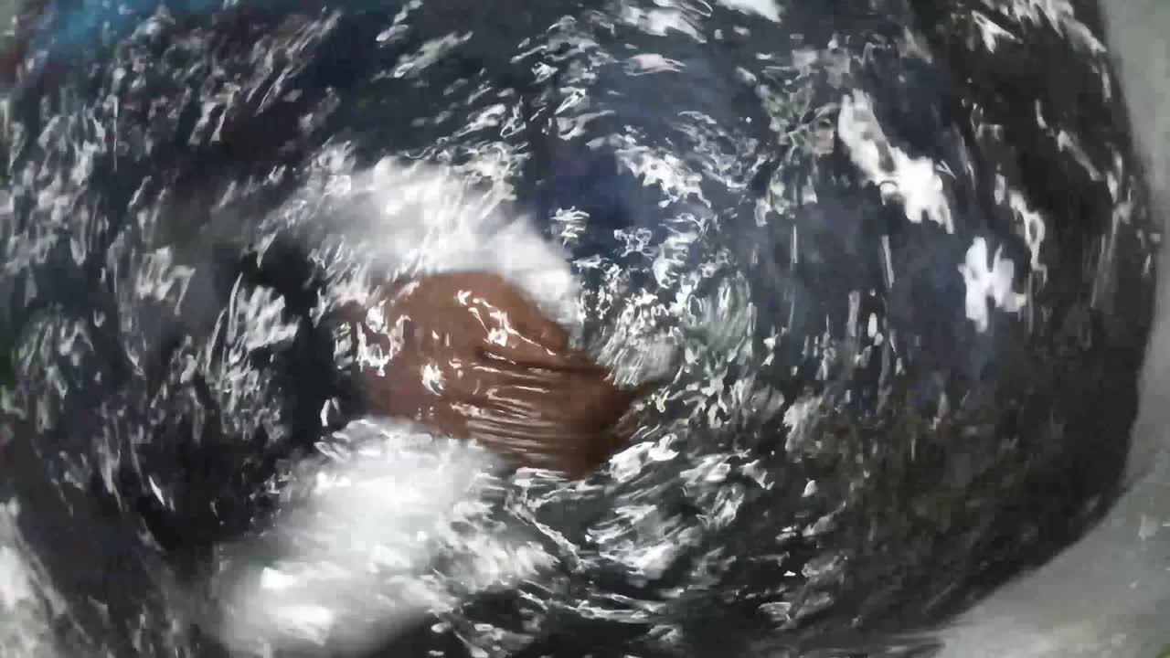 close up of washing machine laundry with clothes spinning in hot water and soap