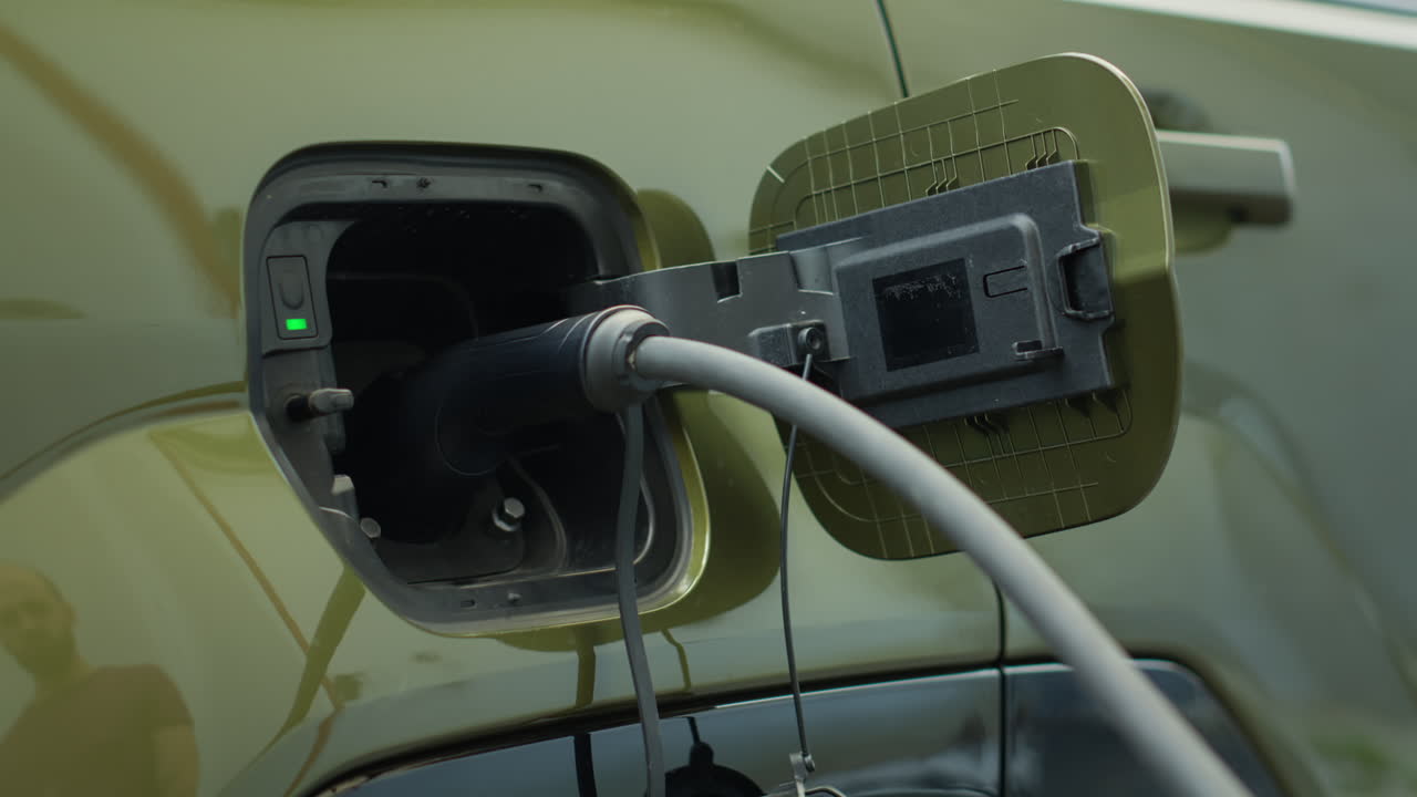 Close Up Of Driver Attaching Electric Cable To Ev Vehicle Charging Port