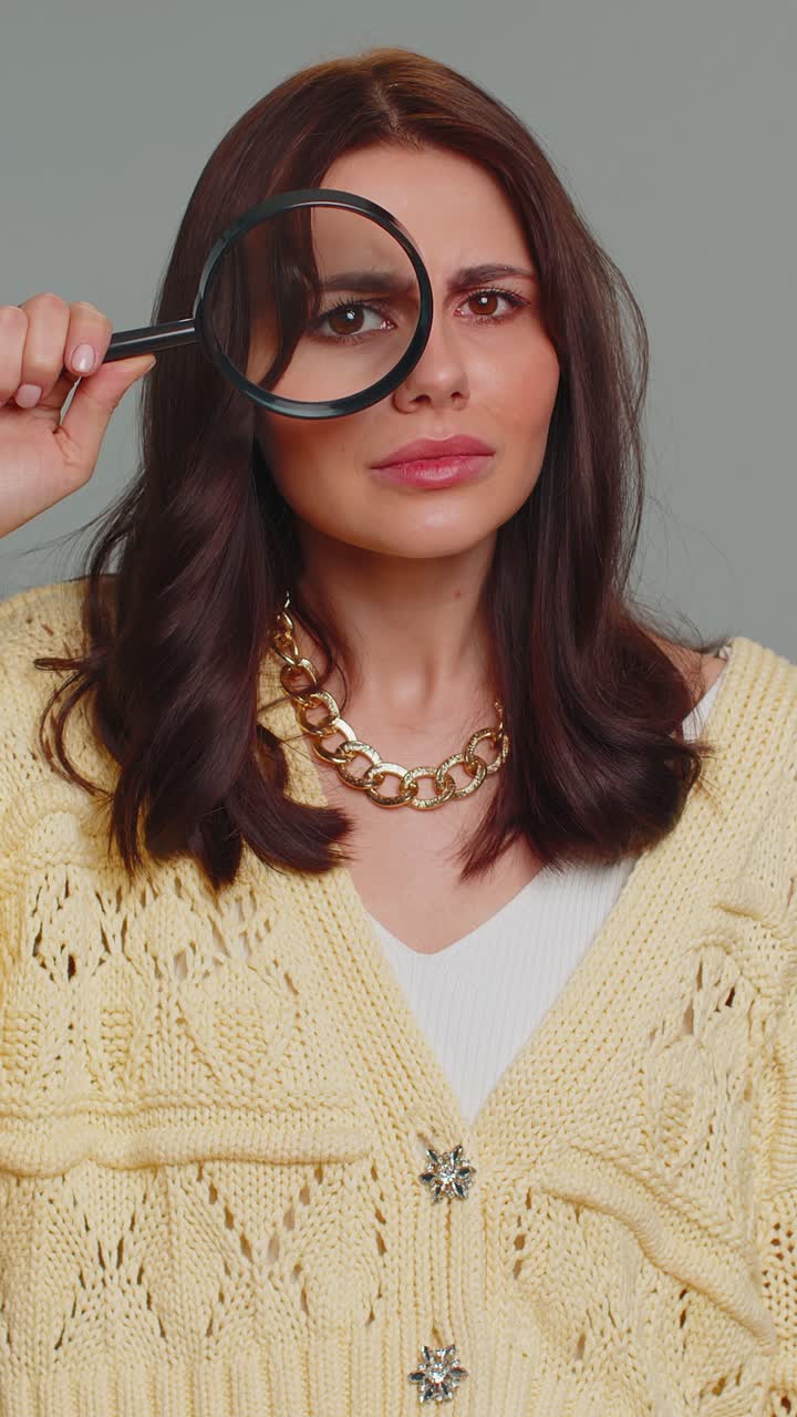 Investigator researcher woman with magnifying glass near face looking into camera with big zoom eye