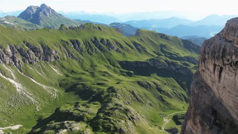 Exuberantes-Prados-Verdes-Se-Extienden-En-Los-Dolomitas,-Yuxtapuestos-A-Los-Imponentes-Riscos-Rocosos-Que-Proyectan-Profundas-Sombras.