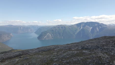 Drohnenaufnahme-Zeigt-MTB-Biker-Auf-Felsigem-Weg-Auf-Dem-Gipfel-Des-Berges-Mit-Meereslandschaft-Im-Hintergrund---Sonniger-Tag-In-Norwegen,-Europa