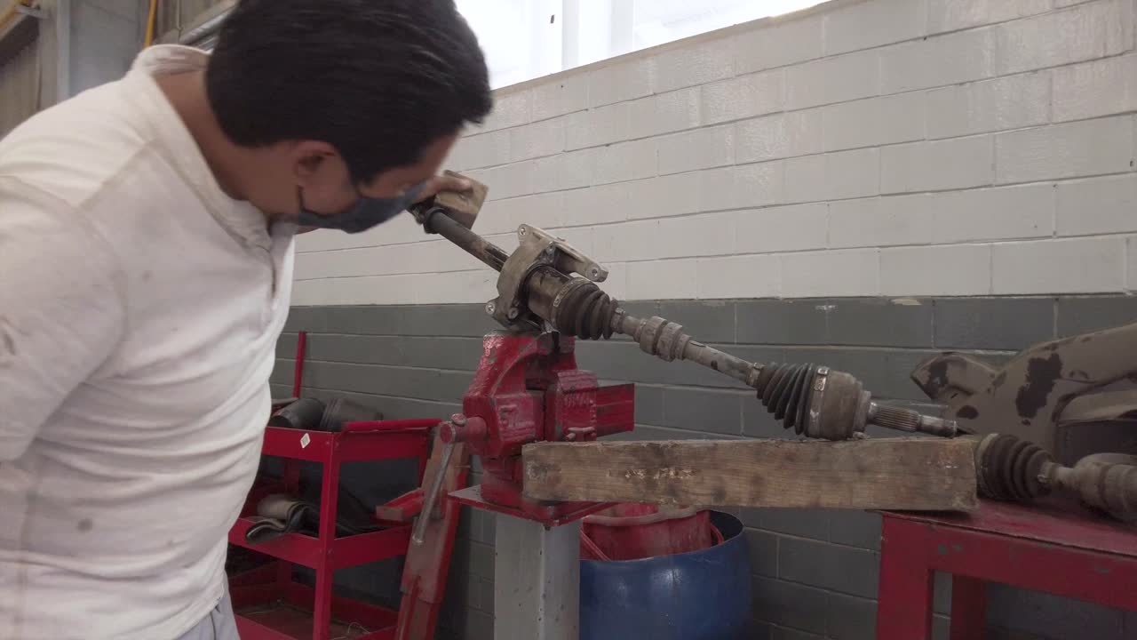 Latin male technician servicing the drive shaft of a car at a workshop station garage at mexico latin-america