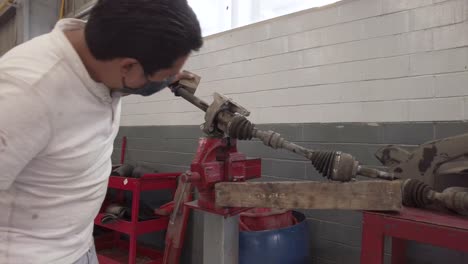 Técnico-Masculino-Latino-Que-Da-Servicio-Al-Eje-De-Transmisión-De-Un-Automóvil-En-Un-Garaje-De-La-Estación-De-Taller-En-México-América-Latina