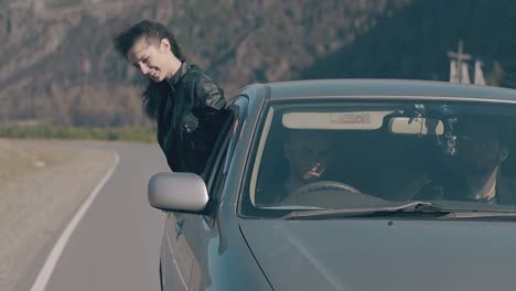 wind plays with young lady hair leaning out of driving car