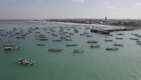 aerial view of indonesian traditional juking boats bobing near the pier on turquoise transparent waves near a tropical island of bali