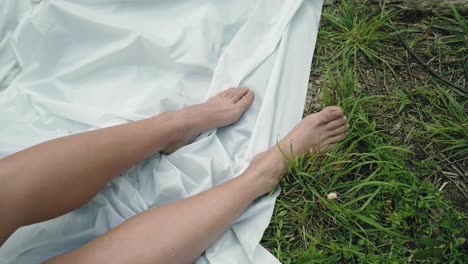 woman bare feet graze linen amidst whispers of green