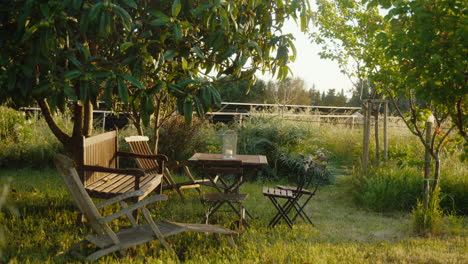 serene garden with wooden furniture under lush trees in mallorca, spain. captures peaceful outdoor ambiance. perfect for travel or nature documentaries.