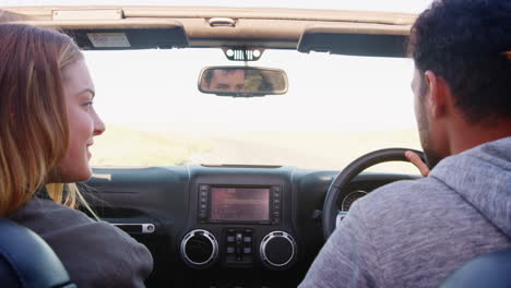 young couple driving with sunroof open, rear passenger pov