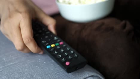 Cerca de la mano de las mujeres sosteniendo el control remoto del televisor