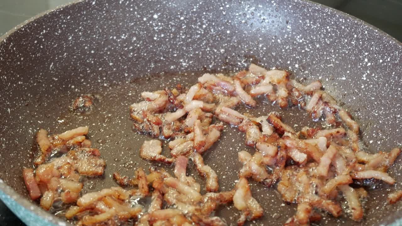 Crispy bacon sizzling in a pan, showing the golden-brown texture and crisp edges