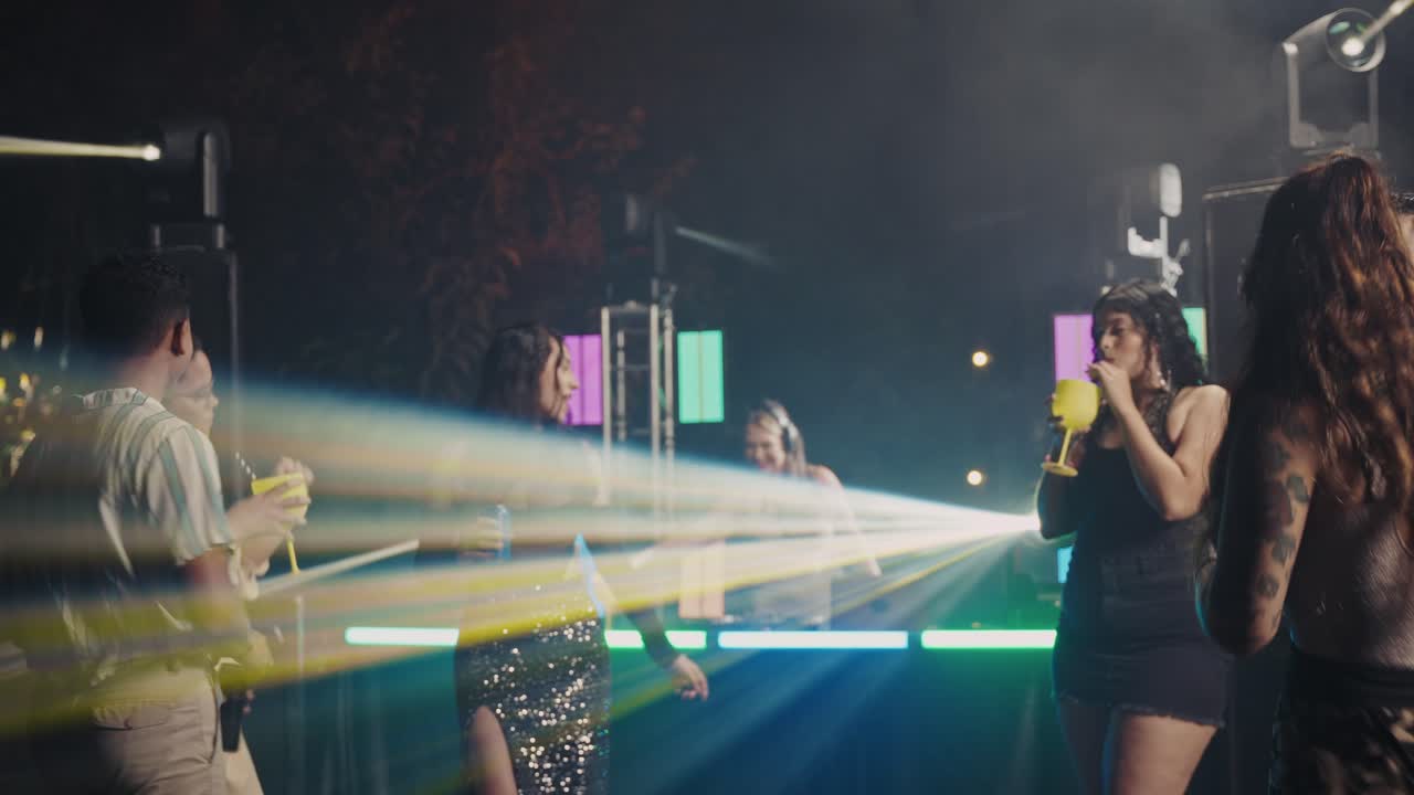 Diverse group of friends dancing and enjoying an outdoor night party with a DJ