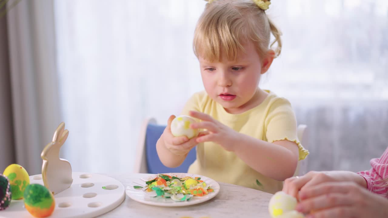 Bambina carina che sguscia uova di Pasqua a casa