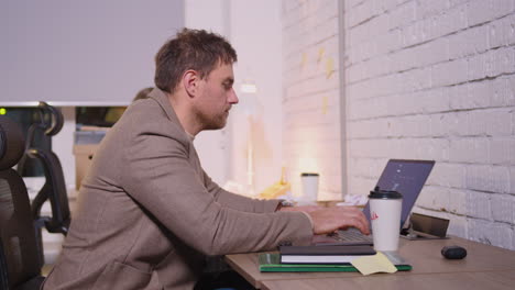 Geschäftsmann-Tippt-Auf-Laptop-Computer-Und-Trinkt-Kaffee-Zum-Mitnehmen-In-Einem-Coworking-Büro