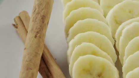 sliced bananas and cinnamon sticks in plate