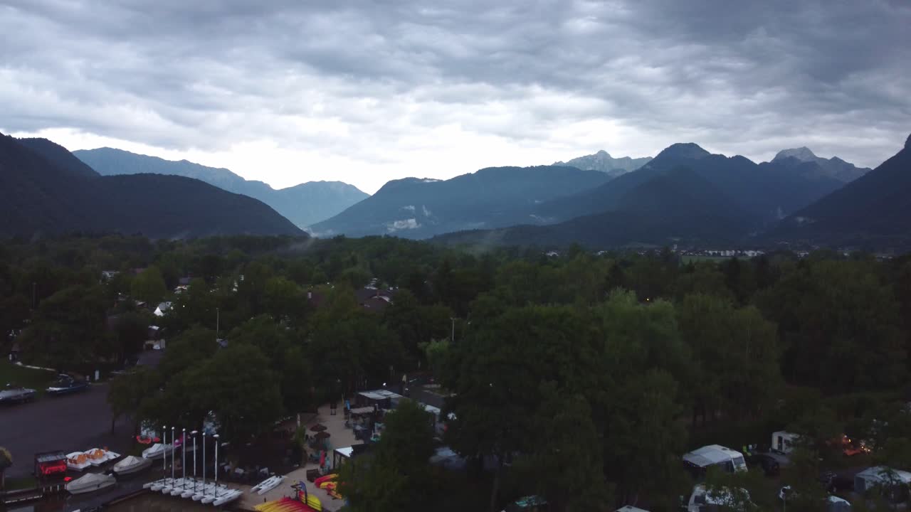 Drone footage lowering over a campsite and marina on Lake Annecy with stunning mountains in the background