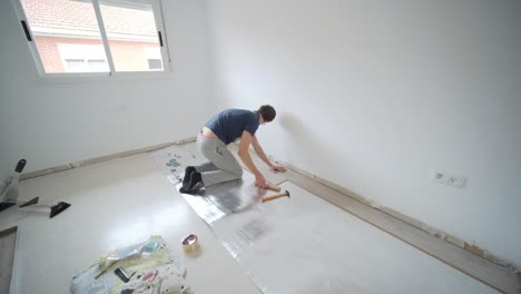 Wide-shot-of-white-man-laying-tiles-in-room