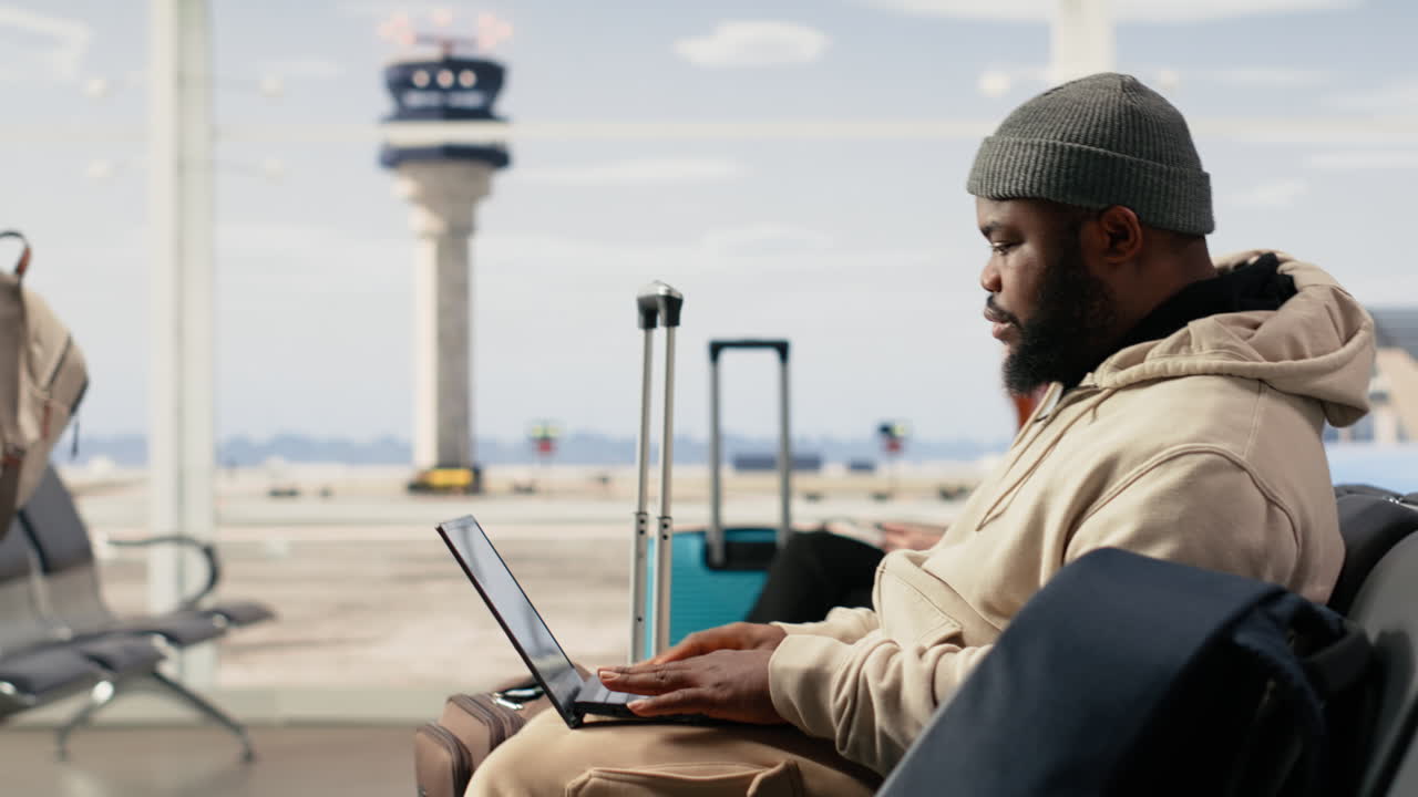 African American Man Working on Laptop in Airport Waiting Area