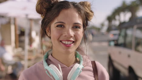 retrato de una joven hermosa mujer hispana sonriendo feliz en una playa soleada con auriculares
