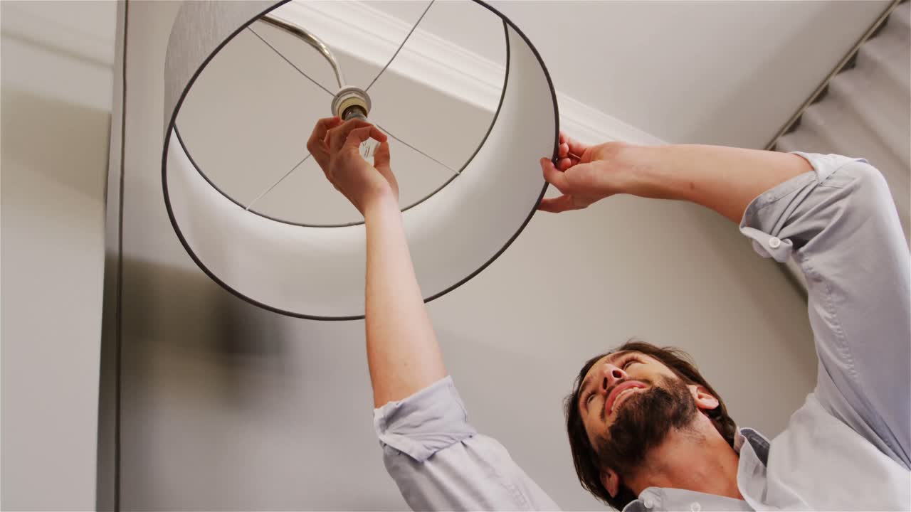 hombre instalando una bombilla en la sala de estar