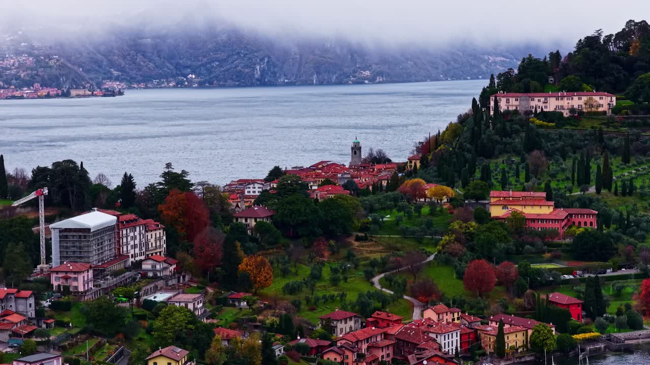 Paesaggio di Bellagio con vista sul lago, caratterizzato da edifici raggruppati e colline circostanti, ripresa aerea con tracking a destra