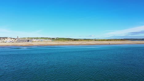 aerial establishing shot flying over tramore beach during summer