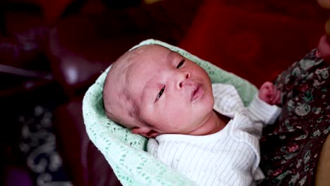 newborn baby boy with shaved head being gently rocked in mothers arms