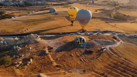 Globo-De-Aire-Caliente-Que-Termina-Un-Recorrido-Turístico-En-Capadocia-Doblado-Y-Furgonetas-Blancas-Esperando-A-Que-Los-Turistas-Los-Lleven-De-Regreso-A-Los-Hoteles-En-Goreme-Turquía