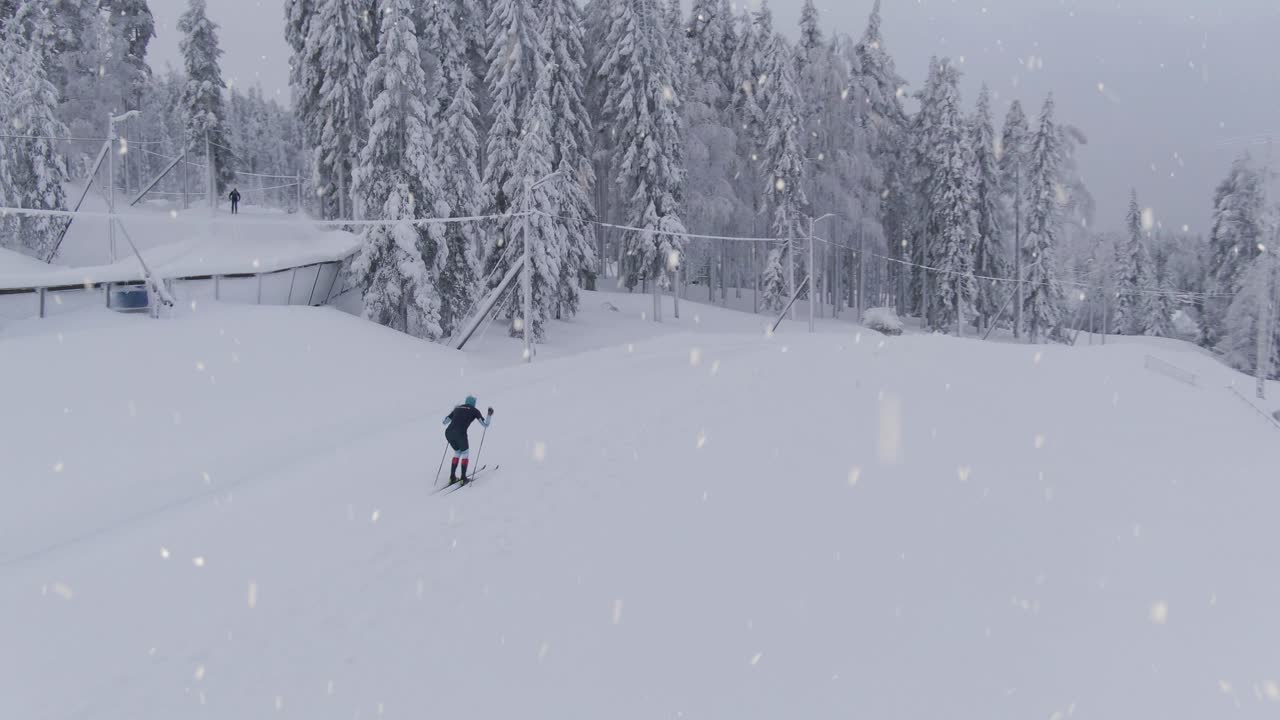 Athlete preparing for winter Olympics in cross country skiing during snowfall, aerial drone shot