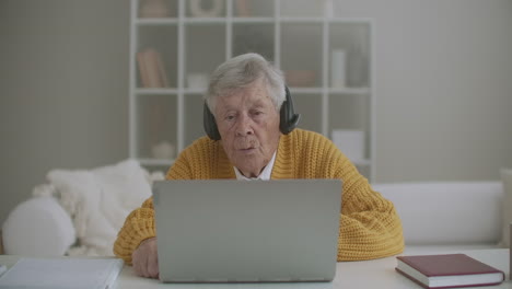 una mujer mayor está usando una computadora portátil para hacer una llamada de video hablando haciendo gestos mostrando el pulgar hacia arriba con el gesto de la mano en el interior. la mujer mayor y el concepto de dispositivos modernos.