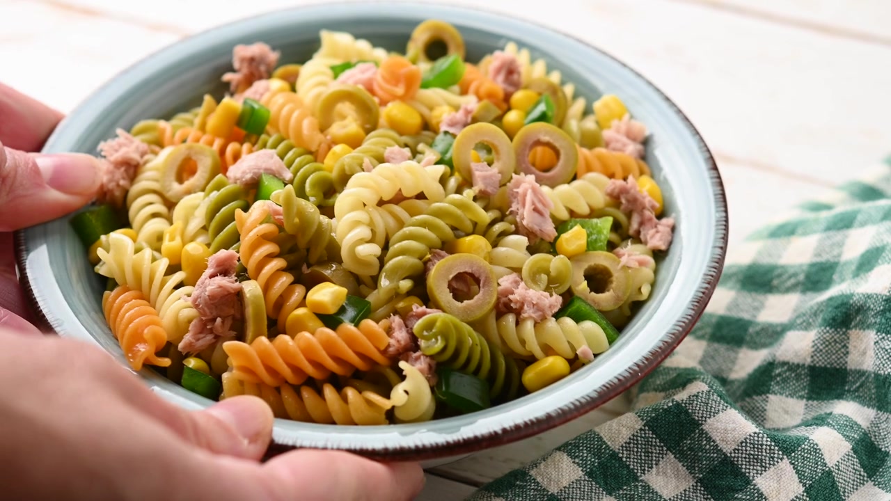 Insalata di pasta con tonno, mais e olive in una ciotola.
