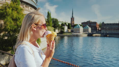 Frau-Tourist-Isst-Eis-Auf-Dem-Hintergrund-Der-Erkennbaren-Aussicht-Auf-Die-Stadt-Stockholm-I