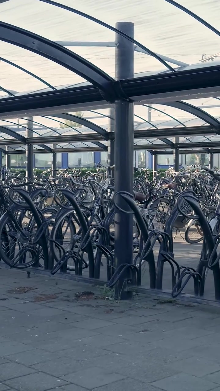 Fileiras de bicicletas estacionadas em um bicicletário coberto ao ar livre.