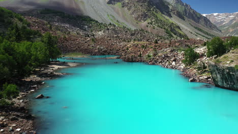 Cinematic-aerial-shot-over-the-turquoise-colored-water-in-the-mountains-at-Naltar-Valley-in-Pakistan,-drone-shot