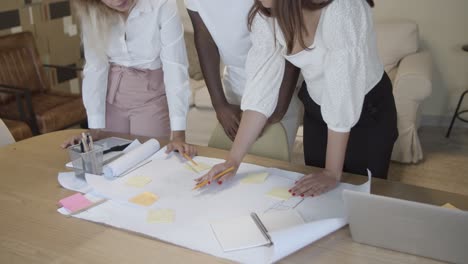 colleagues meeting at table with laptop and big paper sheet