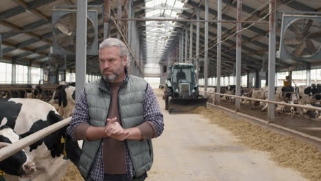 slowmo of dairy farm worker walking through facility