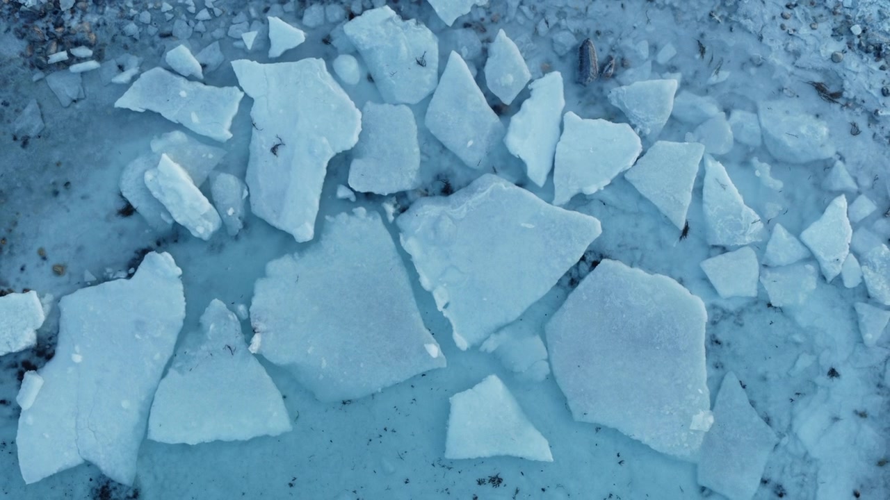 Ripresa aerea ravvicinata di lastre di ghiaccio artico rotte che si sciolgono lungo la costa ghiacciata della Norvegia, con drone.