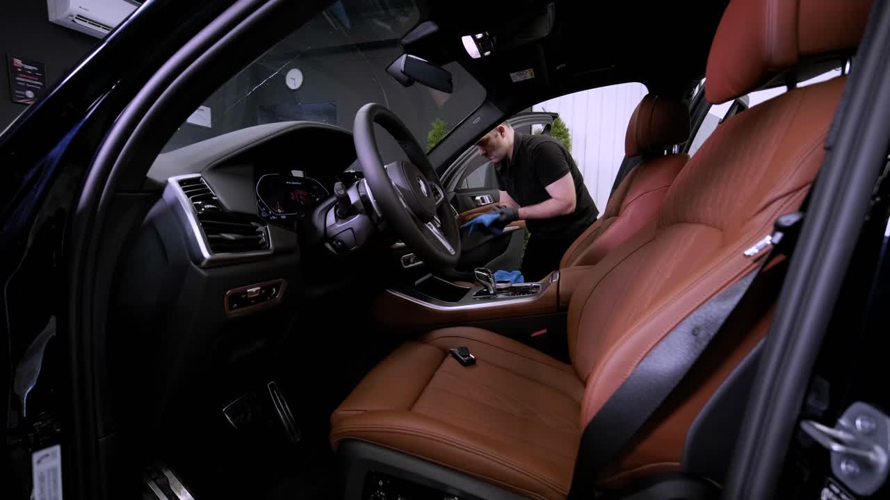 el lavador de coches profesional con guantes negros limpia el coche después de lavar y forrar la cerámica. conceptos de: trabajo profesional, varias herramientas de lavado, limpieza para brillar.