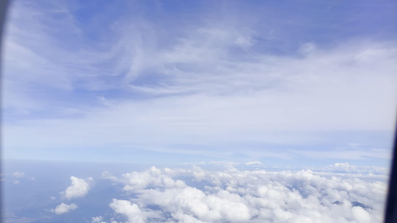 Footage showing clouds in the sky as seen from an airplane window, capturing aerial atmospheric views, soft white formations, and a serene blue horizon, ideal for travel, aviation, and nature visuals