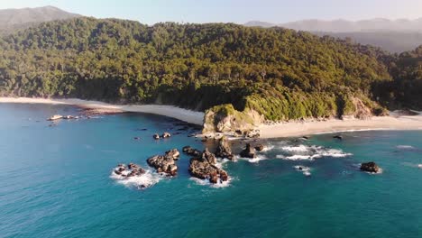 Aerial-orbit-reveal-shot-of-New-Zealand-shore-during-golden-hour