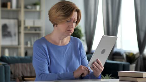 old senior woman reacting to financial loss while using tablet