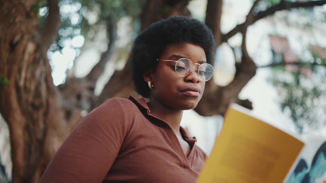 retrato de una hermosa mujer africana leyendo un libro en la calle
