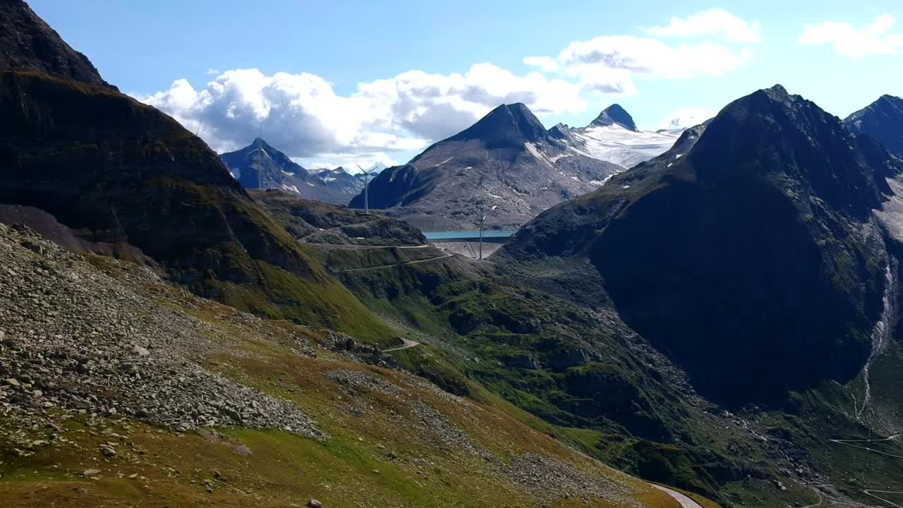 una lenta toma aérea sobre un arroyo alpino rocoso con agua glacial chocando contra rocas de colores claros y muy erosionadas