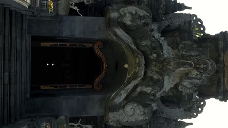 vertical slow tracking shot unveiling the grandeur of the bajra sandhi monument in denpasar, bali, through an impressively adorned golden entrance gate amidst stunning architectural elements