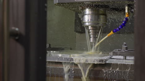 cnc milling machine in action with coolant spraying on metal part during machining