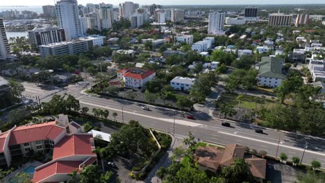 aerial approaching fight over main street of sarasota city in sunlight. towers and housing area with single family hokes in american town. landing sho