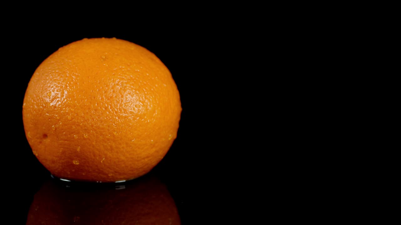 una sola naranja madura gira en la mesa.